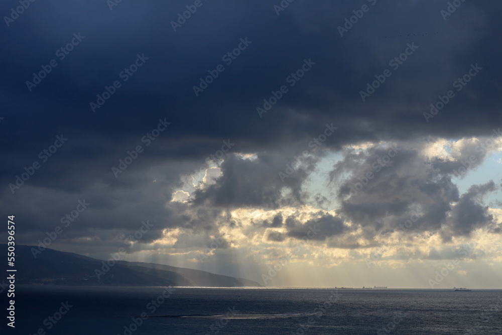 the sun rays shine through the clouds on the sea surface the sun rays shine through the clouds on the sea surface