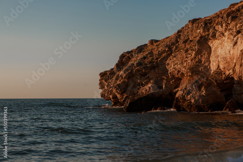 Waves on the sea during sunset. Relaxation, enjoyment. Journey to the ocean, peace and happiness. Colorful, bright, orange sunset. The sun shines through the clouds on the ocean. Beautiful wallpapers