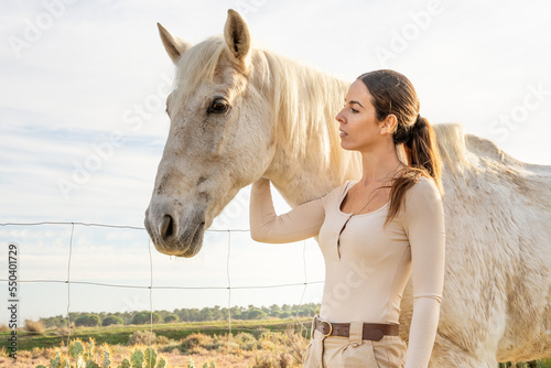 Beautiful portrait of a woman touching her white horse. Girl playing with stallion. True friendship. unconditional love. Loyalty forever. Friends forever. Cowgirl stroking her horse.