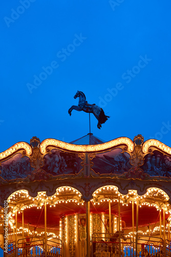 horse on the top of roundabout, galloper. Children's Carousel close up in the night illumination. Outdoor vintage colorful luminous. Retro Shiny Carousel details, horses. vertical photo, bottom view