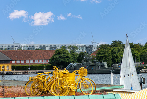 Canvas Print Copenhagen, Denmark - July 24, 2022: Closeup of yellow bike statue set on roof of old toll office, now restaurant on west shore of harbor