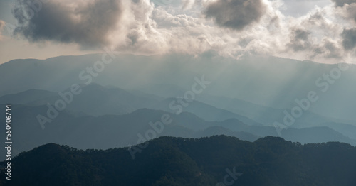 Mountain landscape with bright sun rays shining and cloudy sky in the morning.