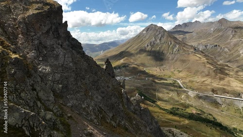 Close aerial shot along rocky peaks discovering a valley with glacier in background french alps