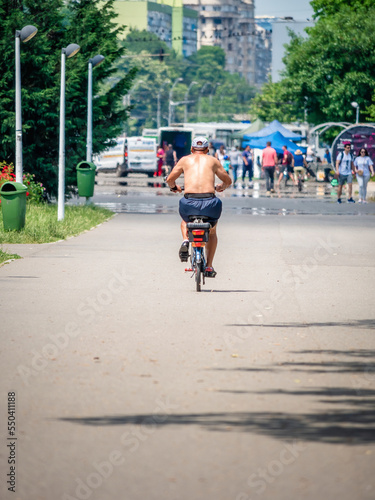 Rear view with a man in the park ridding a bicycle. Ciclyst in Youth Park (Tineretului) Bucharest, Romania. photo