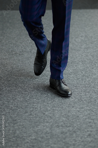 A man in shoes is walking down the corridor ahead, on camera, close-up.Successful businessman goes to a business meeting