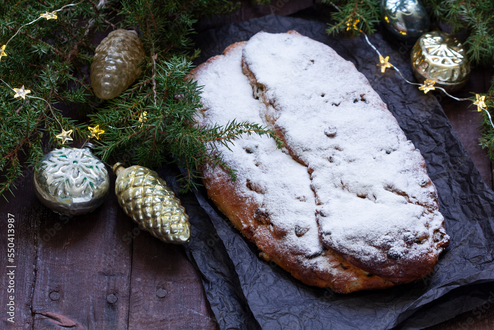 Christmas stollen with dried fruits, nuts and spices, Christmas decorations on a dark wooden background. Rustic style.