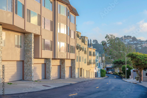 Roadside apartment buildings with attached garage and a view of mountain at the back