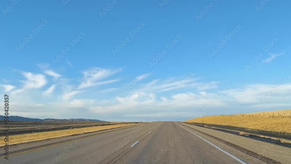 Point of View Driving a car on a deserted highway in Wyoming under bright blue sky. Point of View Driving a car on a deserted highway in Wyoming under bright blue sky.