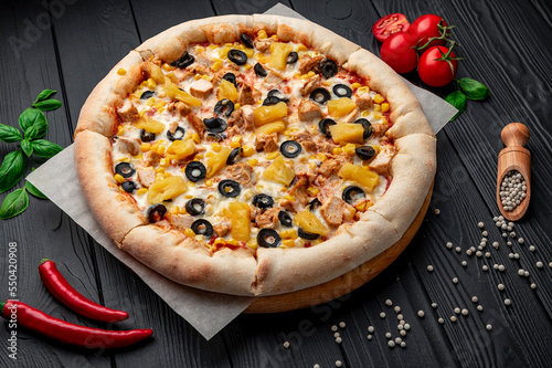 Delicious pizza with chicken meat, pineapple, corn and olives