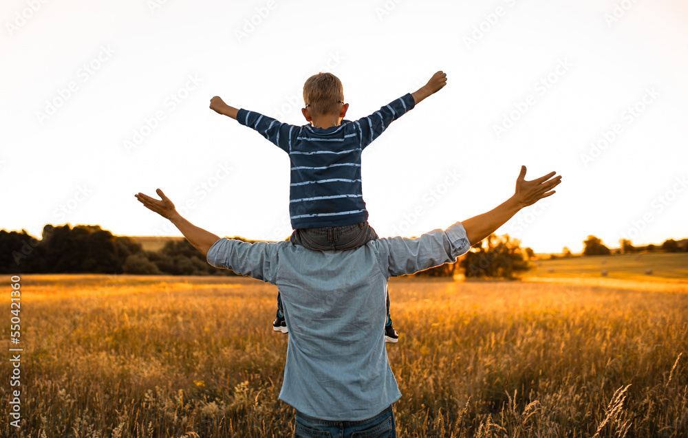 Happy joyful father and son in a nature meadow field feeling free Happy joyful father and son in a nature meadow field feeling free