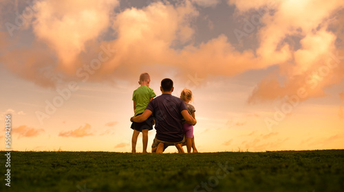 Fatherhood, and family parenting concept. Father and his children spending time together in nature field looking out to the sunset view. 