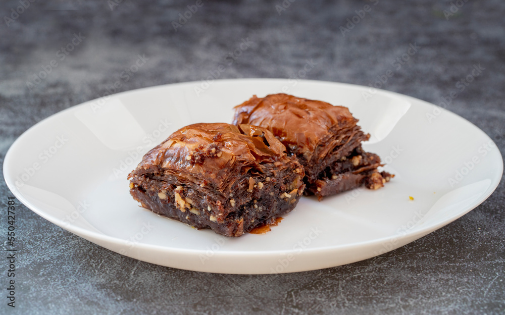 Chocolate baklava on a white plate. Turkish style chocolate baklava presentation and service. Horizontal view. Chocolate baklava on a white plate. Turkish style chocolate baklava presentation and service. Horizontal view.
