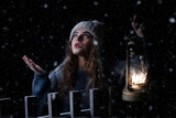 A girl illuminates her way on the snow with a lamp. Studio photo.
