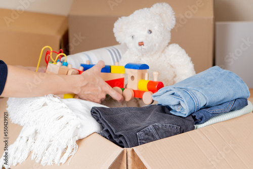 Woman hands collecting donation box with clothes, bed linen, kid toys. Donations for charity, help low income families, declutter, moving moving into new home, recycling, sustainable living