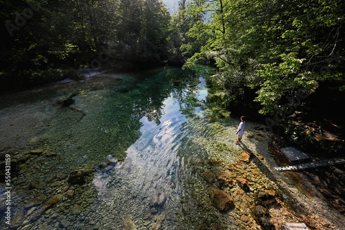 Top view of boy stand in emerald green water of the river Sava Bohinjka in Julian Alps, Ukanc, Slovenia. photo