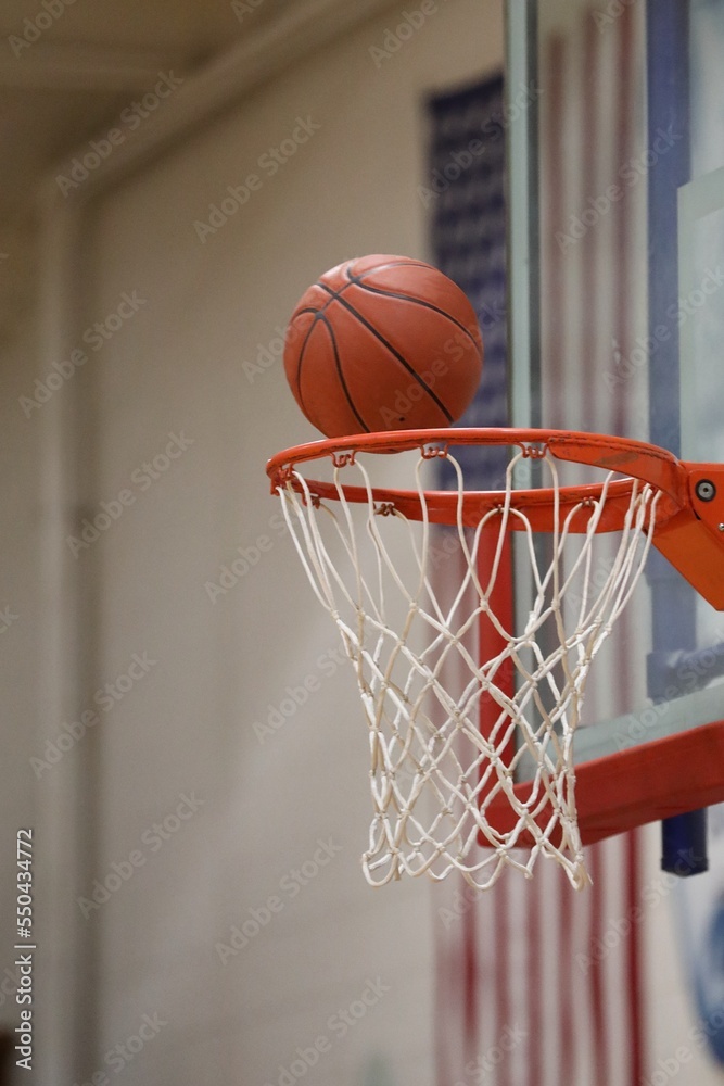 basketball scoring through net with red, white, and blue flag in background