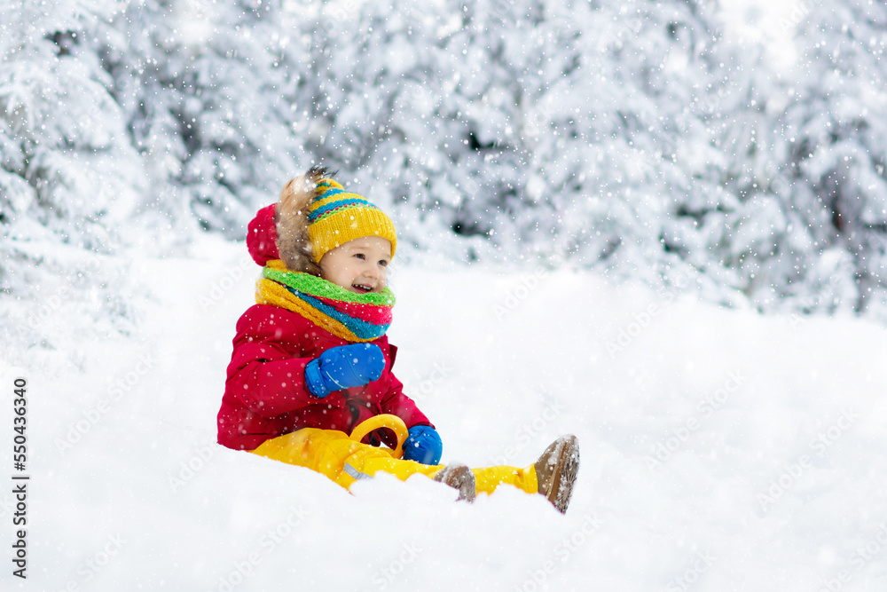 Baby on sled ride. Child sledding. Kid on sledge