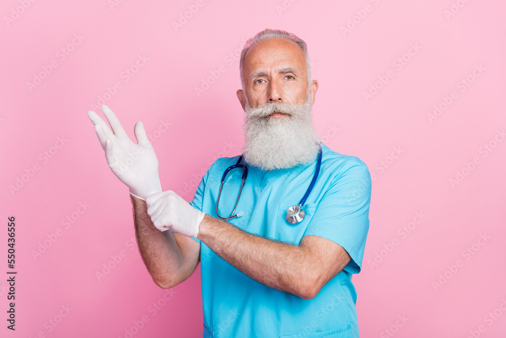Photo of qualified man therapist wear sterile gloves prepare for heart surgery isolated on pastel color background Photo of qualified man therapist wear sterile gloves prepare for heart surgery isolated on pastel color background