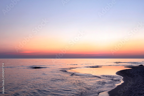 Empty Baltic Sea beach landscape Orange horizon above the water. Scenic seascape  with sunrise sky. Beautiful dawn by the sea  reflections in the calm water.