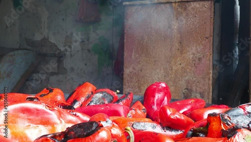 Roasting red peppers for a smoky flavor and quick peeling. Thermal processing of the pepper crop on metal circle. Brazier container used to burn charcoal fuel for cooking or heating. Bulgarian pepper photo