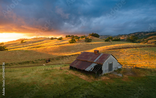 Spectacular sunset colors and light over an old barn in the East Bay hills, near San Jose, California photo