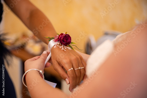 Bild auf Leinwand Bride places a flower corsage on the hand of her maid of honor