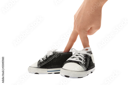Woman's (mother's) fingers imitating first baby's steps with cute small baby's sneakers, isolated photo.