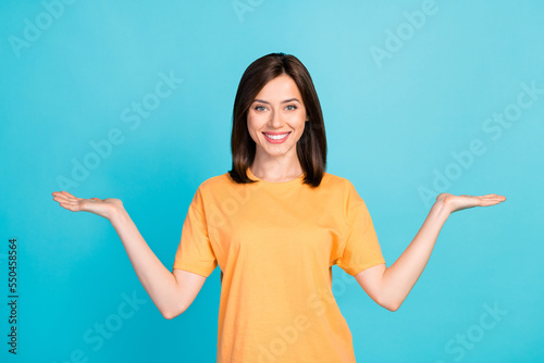 Portrait of charming positive person arms palms hold empty space vs scales isolated on blue color background