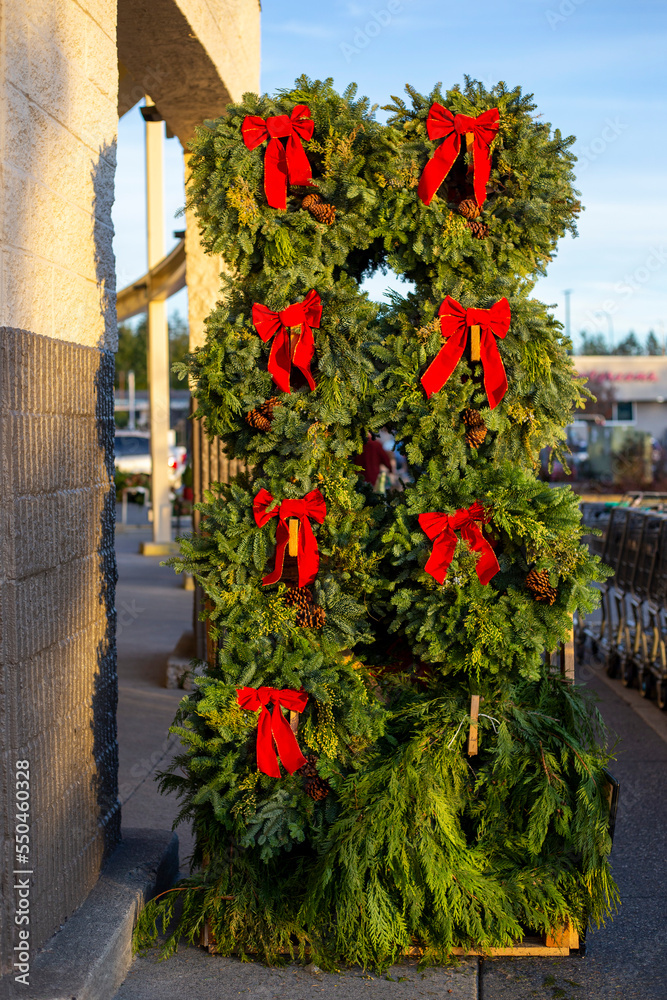 Fototapeta premium Christmas wreaths from pine branches with red bow at showcase outdoors