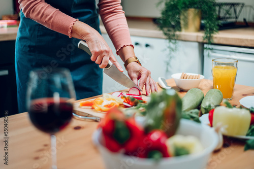 Senior woman hands chopping vegetables on a wooden board in the kitchen