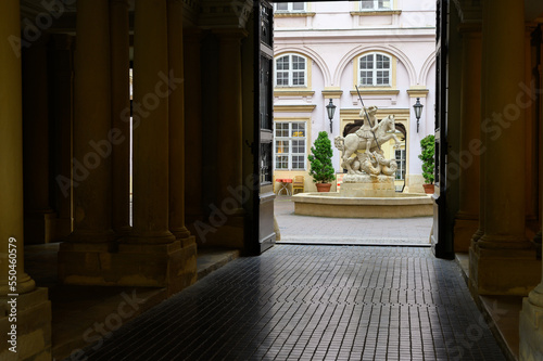 Photography A fountain with a statue of Saint George fighting a dragon in the courtyard of Primate's Palace in Bratislava, Slovakia