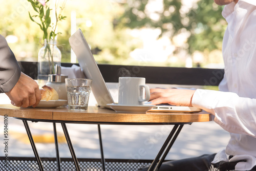 Man sitting outdoors typing on his laptop, cup of coffee on the table