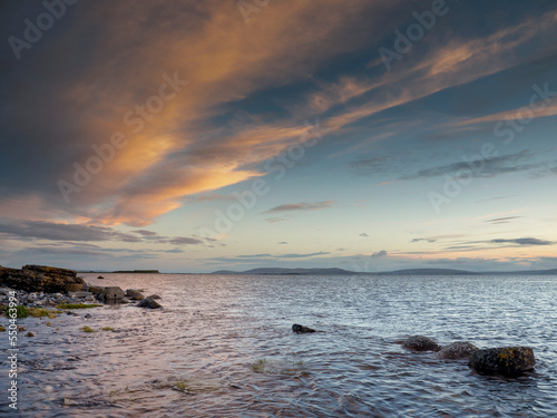 Stunning sunset saturated cloudy sky over ocean and coast. Nature scene. Nobody. Calm and peaceful mood.