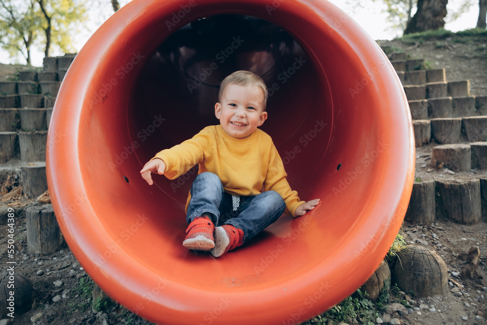 a 2-3-year-old child rolls down a red slide on the playground
