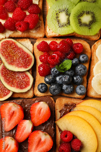 Fototapeta Naklejka Na Ścianę i Meble -  Tasty toasts with different spreads and fruits on wooden table, flat lay