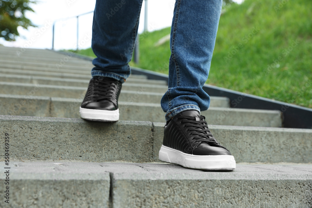 Man in stylish black sneakers walking down stairs, closeup Man in stylish black sneakers walking down stairs, closeup