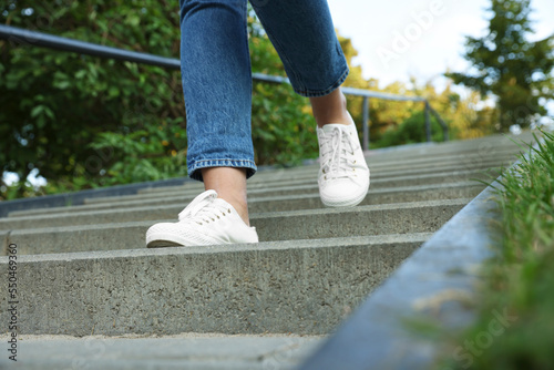 Woman in stylish black sneakers walking down stairs, closeup