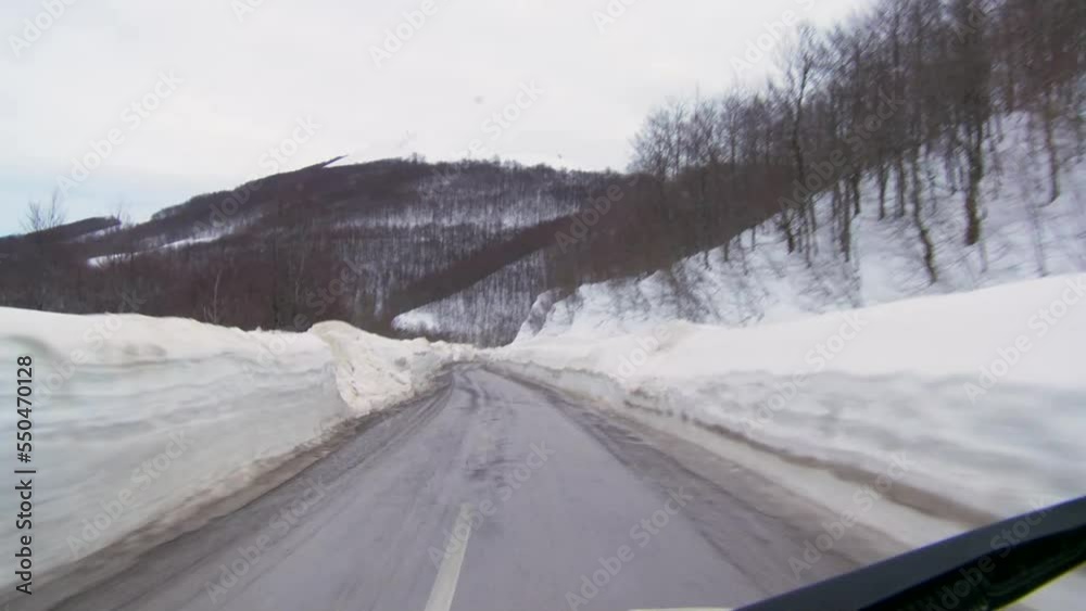Driving on the road fenced with snow. Road with a large layers of snow Driving on the road fenced with snow. Road with a large layers of snow