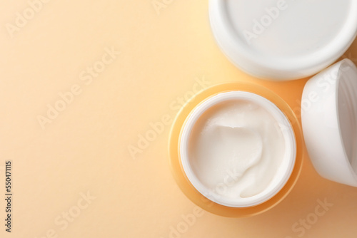 Jars of face cream on beige background  flat lay. Space for text
