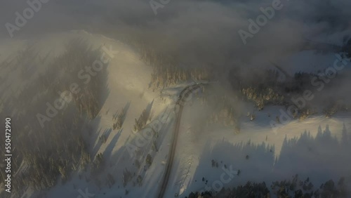 Aerial View of Misty Sunny Morning Above Snow Capped Mountain Hills and Peaks. Flying Above Hayden Pass, Colorado USA at Sunrise photo