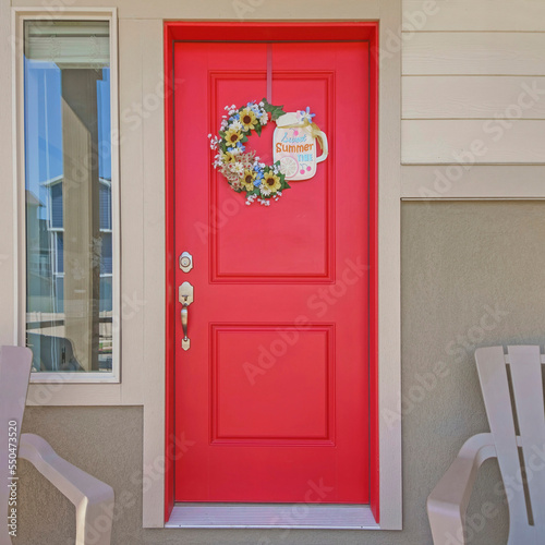 Square Entrance exterior of a house with two armchairs and red front door with wreath