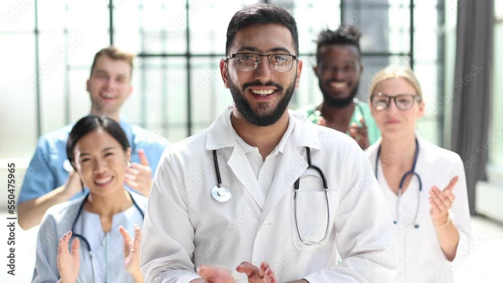group of diverse smiling doctors applauding together.