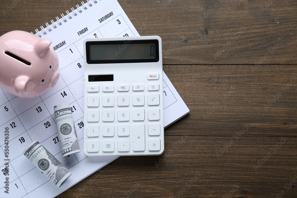 Flat lay composition with piggy bank and calculator on wooden table, space for text. Paying bills concept Flat lay composition with piggy bank and calculator on wooden table, space for text. Paying bills concept