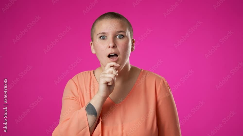Pretty thinking non binary gender fluid young woman 20s, looks at camera gives mind blown gesture showing explosion of ideas posing on pink background.