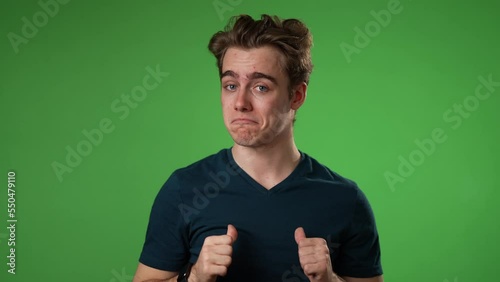 Portrait of smiling young hipster man 20s pointing to self giving thumbs up okay gesture isolated on green screen background in studio in slow motion photo