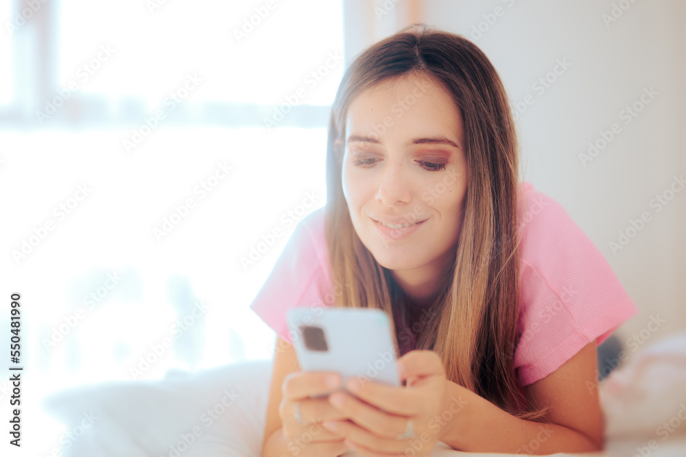 Happy Woman Checking her Smartphone Resting in Bed. Girl relaxing and texting siting in her bedroom
Happy Woman Checking her Smartphone Resting in Bed. Girl relaxing and texting siting in her bedroom