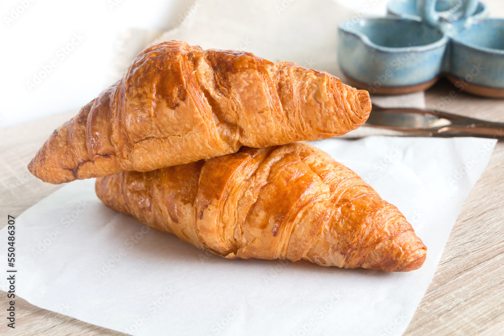 Two french croissant on the grey wooden table decorated with napkin.