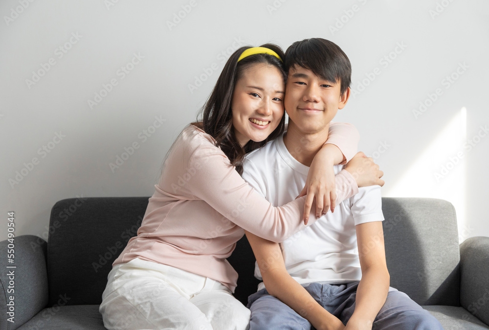 Laughing and hugging asian brother and sister with care and love on sofa at home. Laughing and hugging asian brother and sister with care and love on sofa at home.