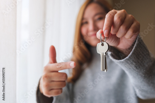 Blurred of a woman holding and pointing finger at the keys for real estate concept
