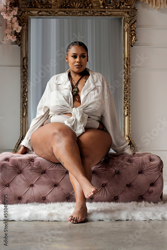 Plus size Black woman sitting on pink bench in front of mirror